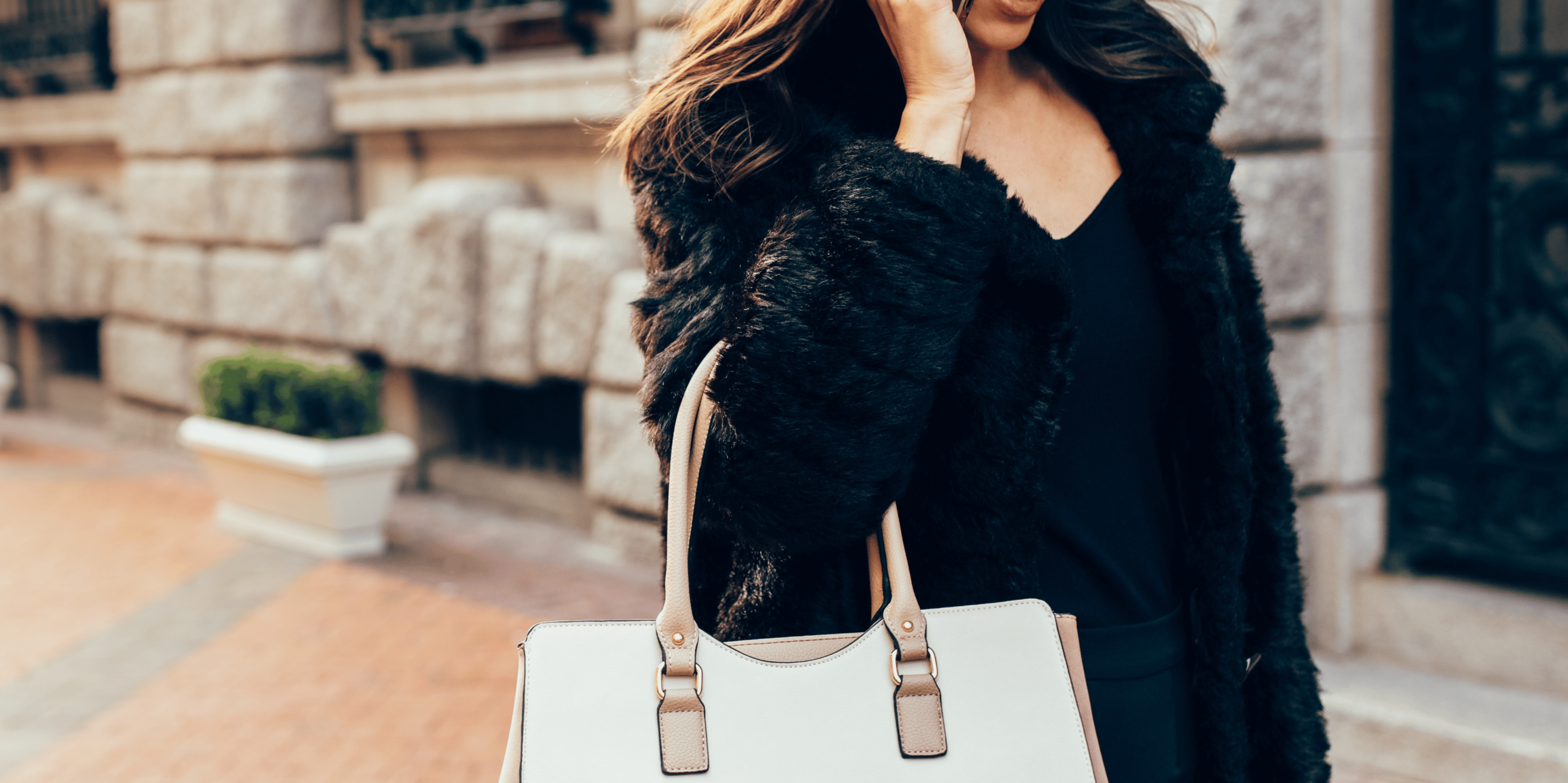 Should You Take Your Designer Purse on Vacation to Europe. Woman walking and talking on cell phone with white and beige designer purse. Travel in Europe, European Travel with fancy purses. Pickpocketing in Europe. Safety in Europe.